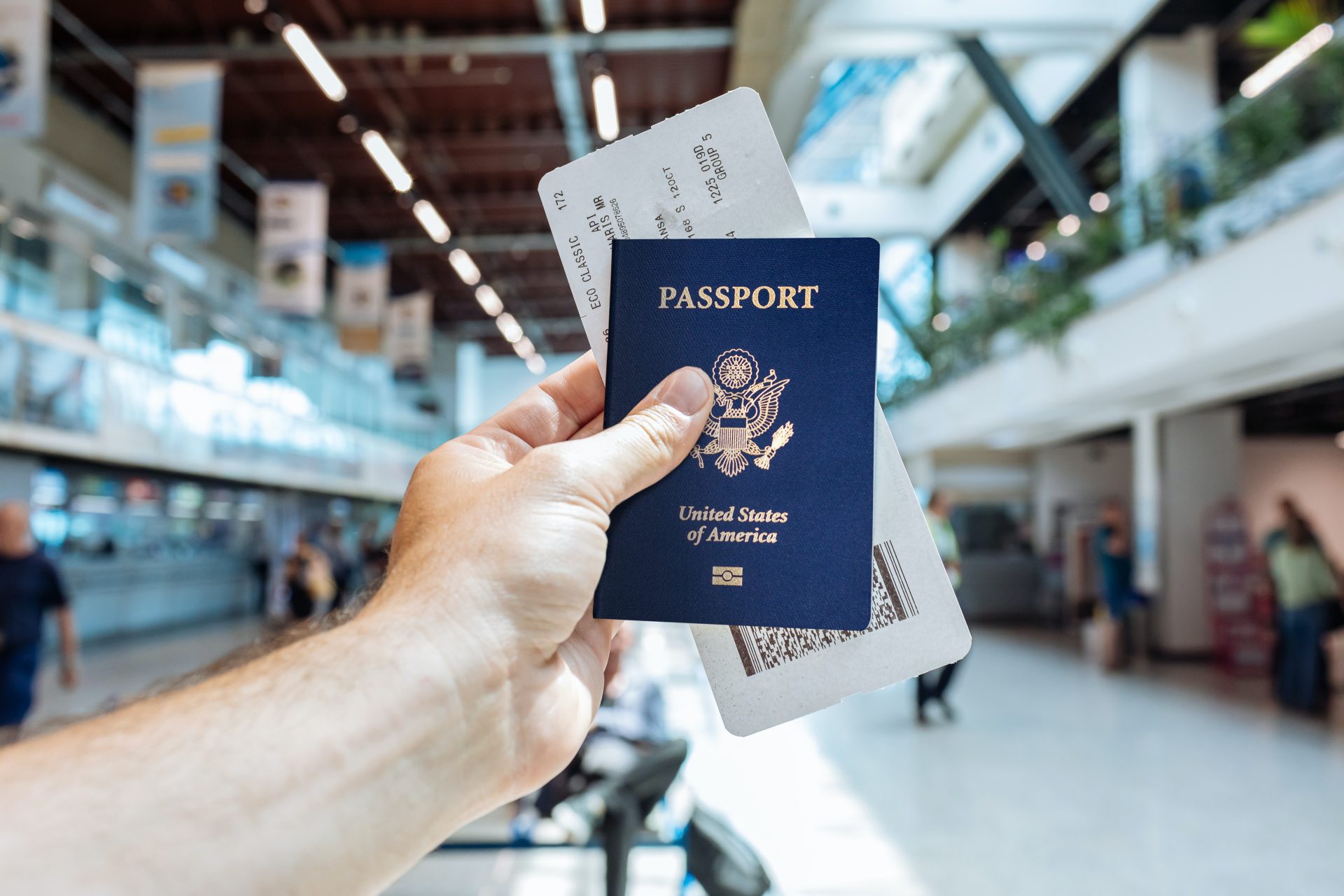 pasaporte de estados unidos con un pase de abordar adentro y el aeropuerto de Estados Unidos al fondo.