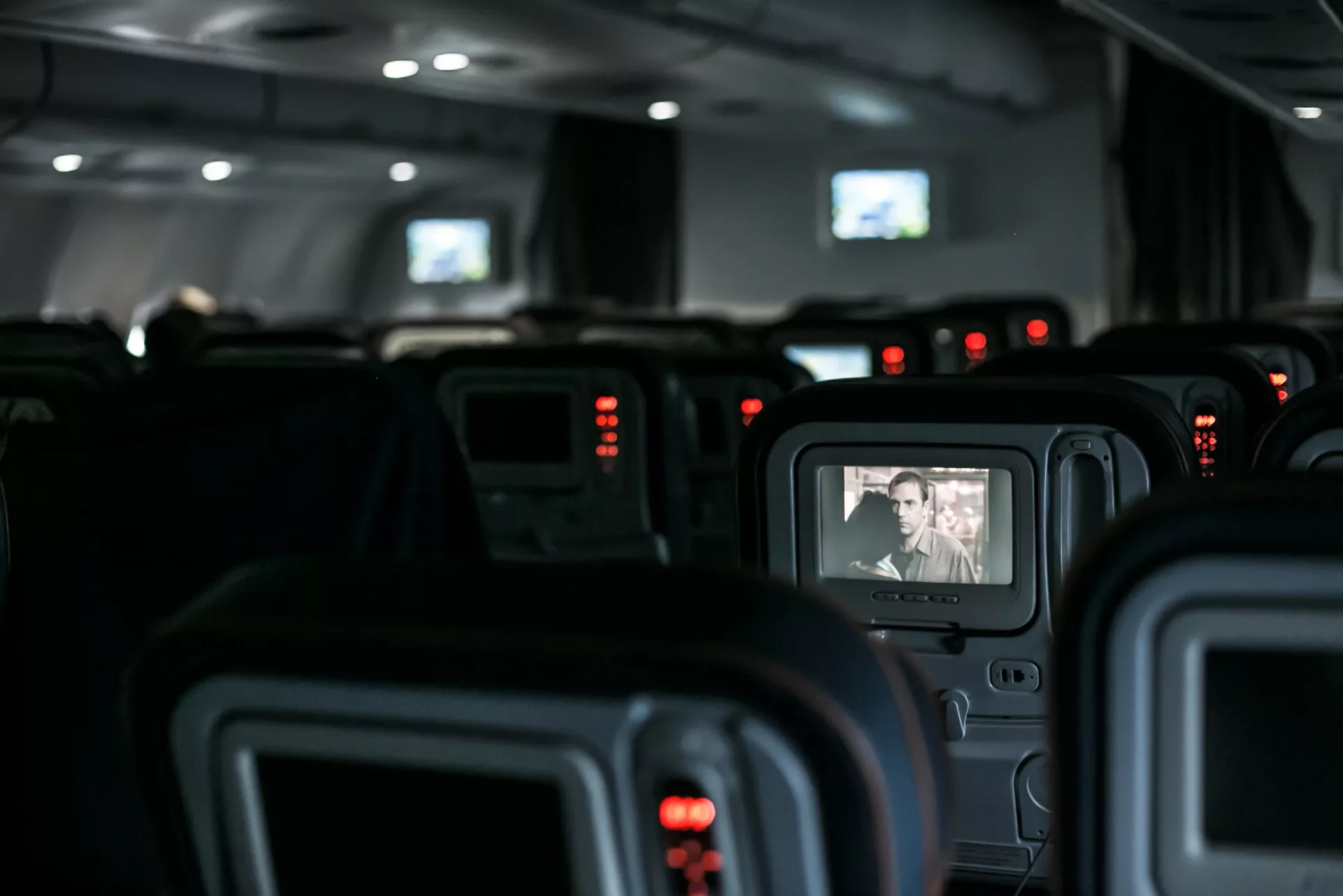 asientos de avión con las pantallas prendidas.